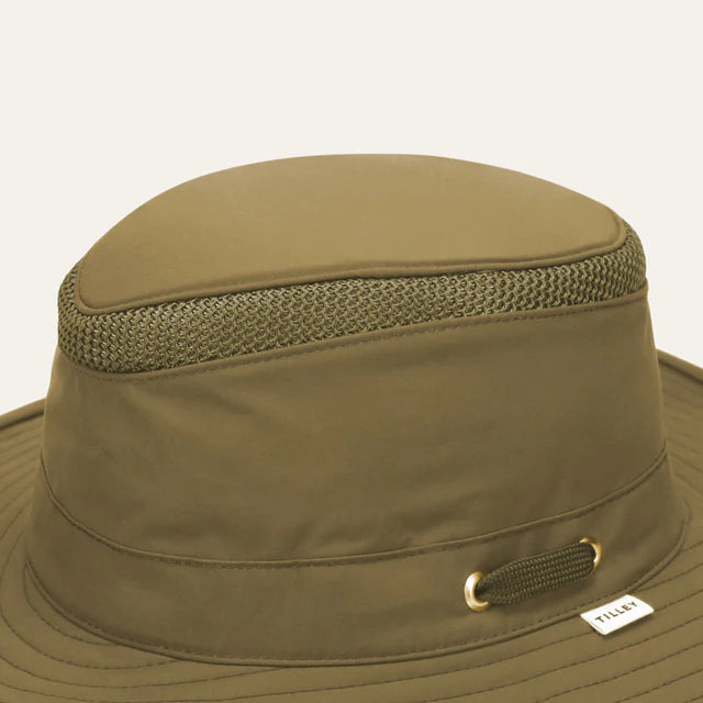 Khaki wide-brimmed hat with mesh and brand label on a beige background