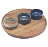 Wooden tray with four ceramic bowls of different colors on a white background