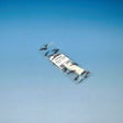 A packaged white plastic replacement part in clear plastic wrapping with a white label, photographed against a blue gradient background.